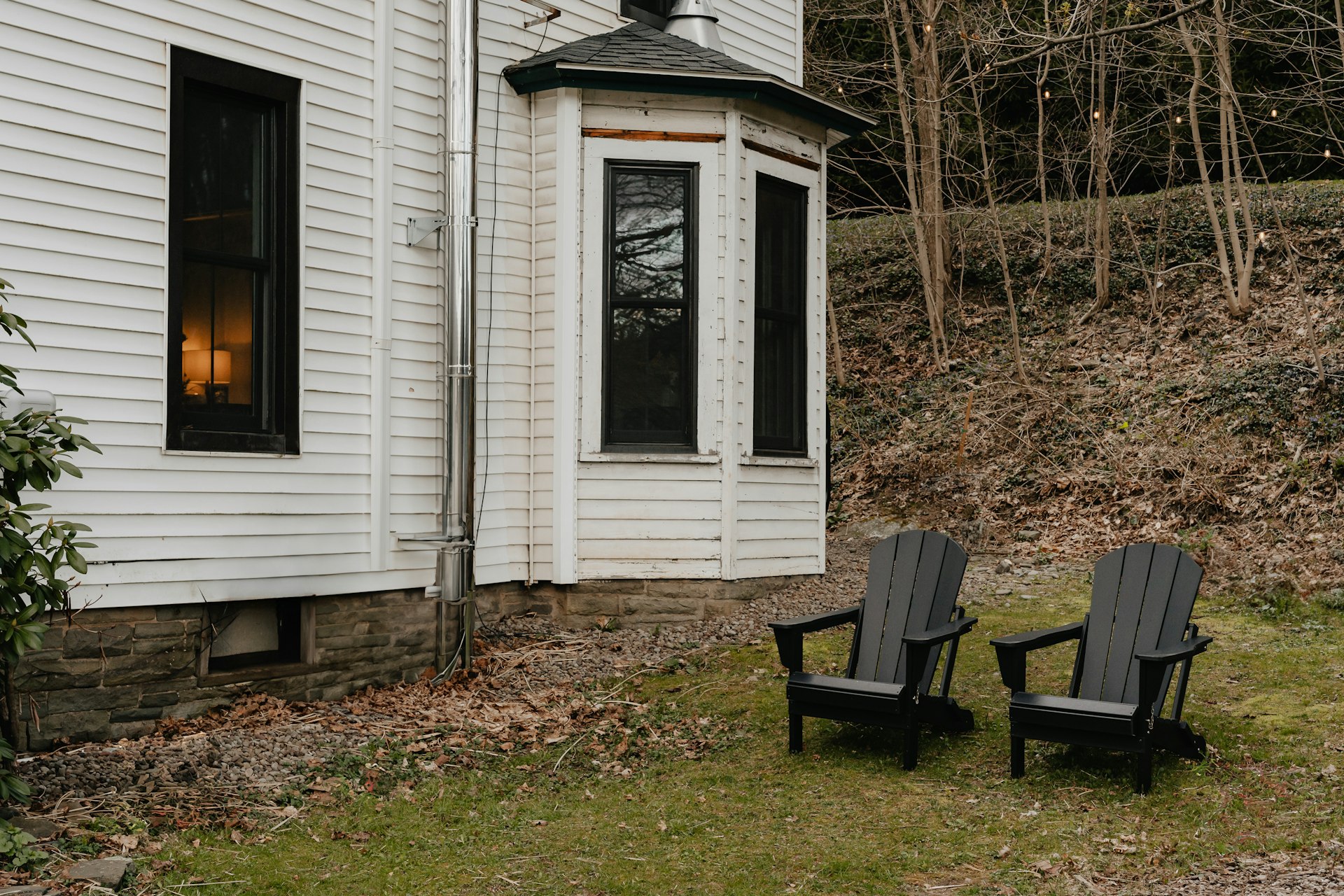 two black chairs sitting in front of a white house
